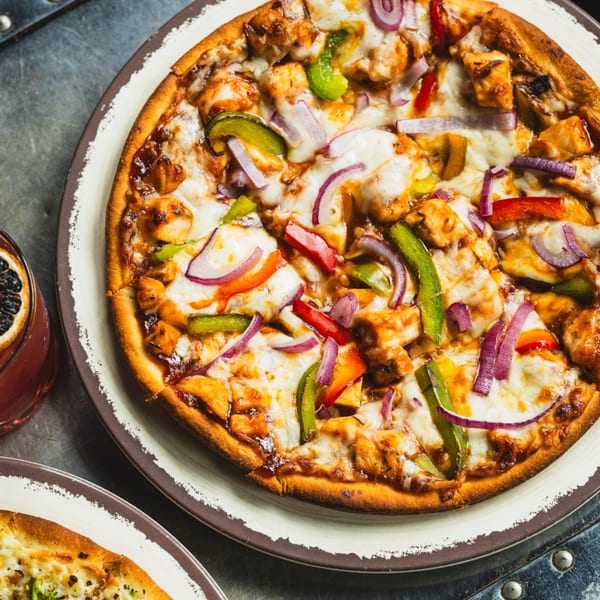 Close-up of a Matilda BBQ chicken pizza with red onions, green and red bell peppers.
